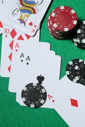 Photo of Casino chips and playing cards on green table, flat lay