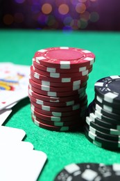Photo of Casino chips and playing cards on green table, closeup