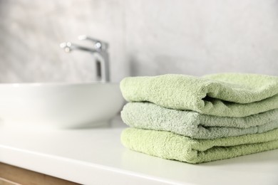 Photo of Fresh terry towels near sink in bathroom