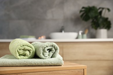 Photo of Fresh terry towels on wooden table in bathroom. Space for text