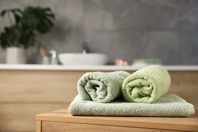 Photo of Fresh terry towels on wooden table in bathroom. Space for text