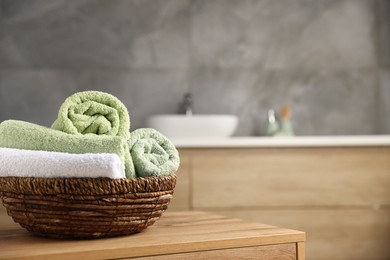 Photo of Fresh terry towels on wooden table in bathroom. Space for text