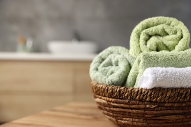 Photo of Fresh terry towels on wooden table in bathroom, closeup. Space for text