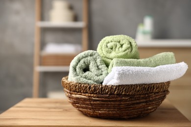 Photo of Fresh terry towels on wooden table in bathroom, closeup. Space for text
