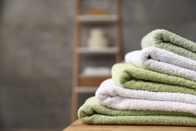 Photo of Fresh terry towels on wooden table in bathroom, closeup. Space for text