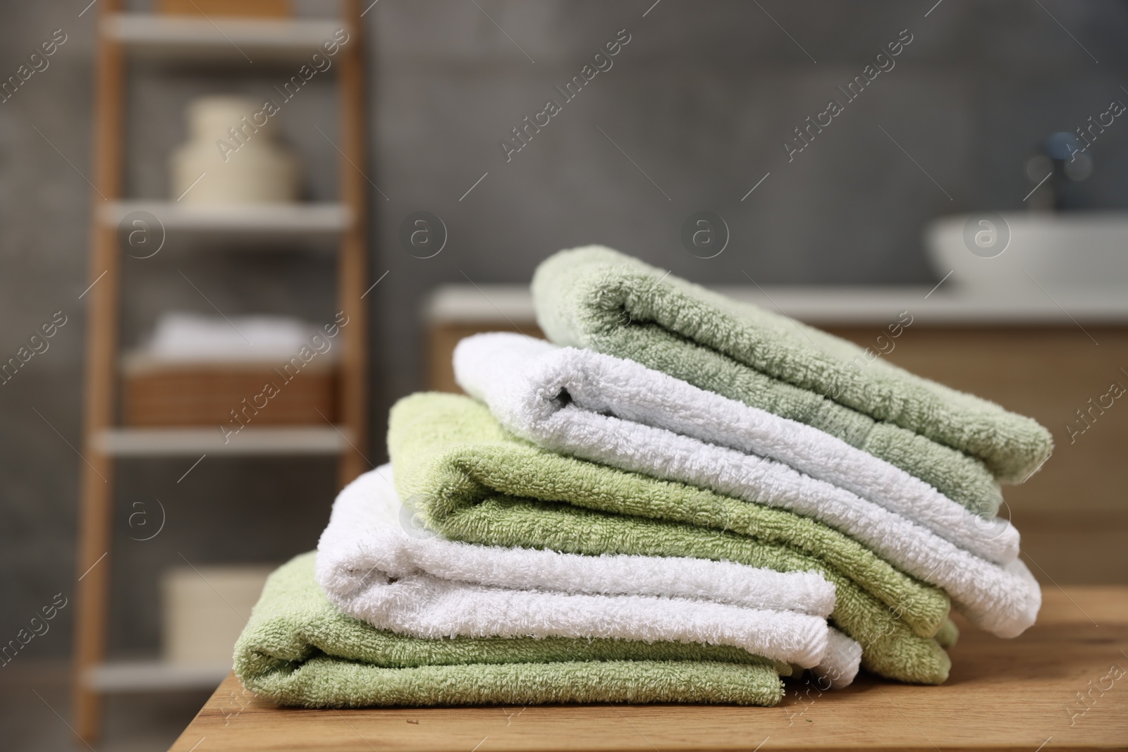 Fresh terry towels on wooden table in bathroom, closeup. Space for text Photo of Fresh terry towels on wooden table in bathroom, closeup. Space for text