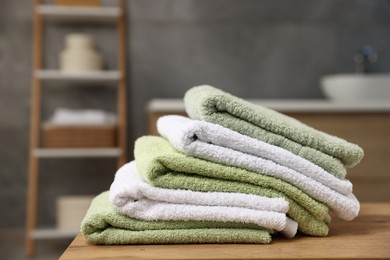 Photo of Fresh terry towels on wooden table in bathroom, closeup. Space for text