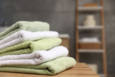 Photo of Fresh terry towels on wooden table in bathroom, closeup. Space for text