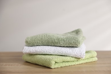 Photo of Folded fresh terry towels on wooden table. Space for text