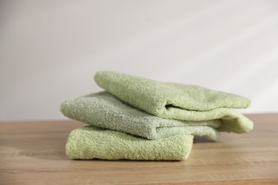 Photo of Folded fresh terry towels on wooden table. Space for text