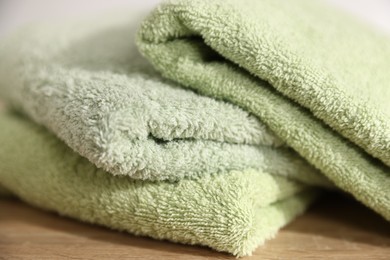 Photo of Fresh terry towels on wooden table, closeup