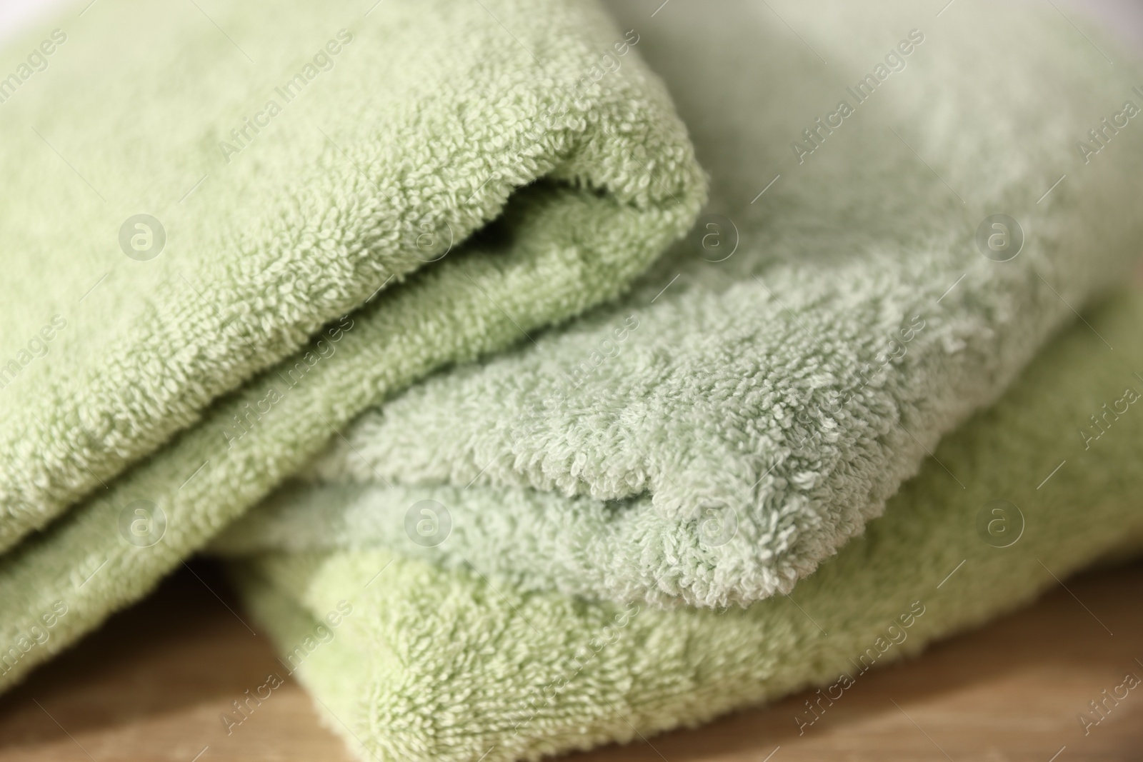 Fresh terry towels on wooden table, closeup Photo of Fresh terry towels on wooden table, closeup