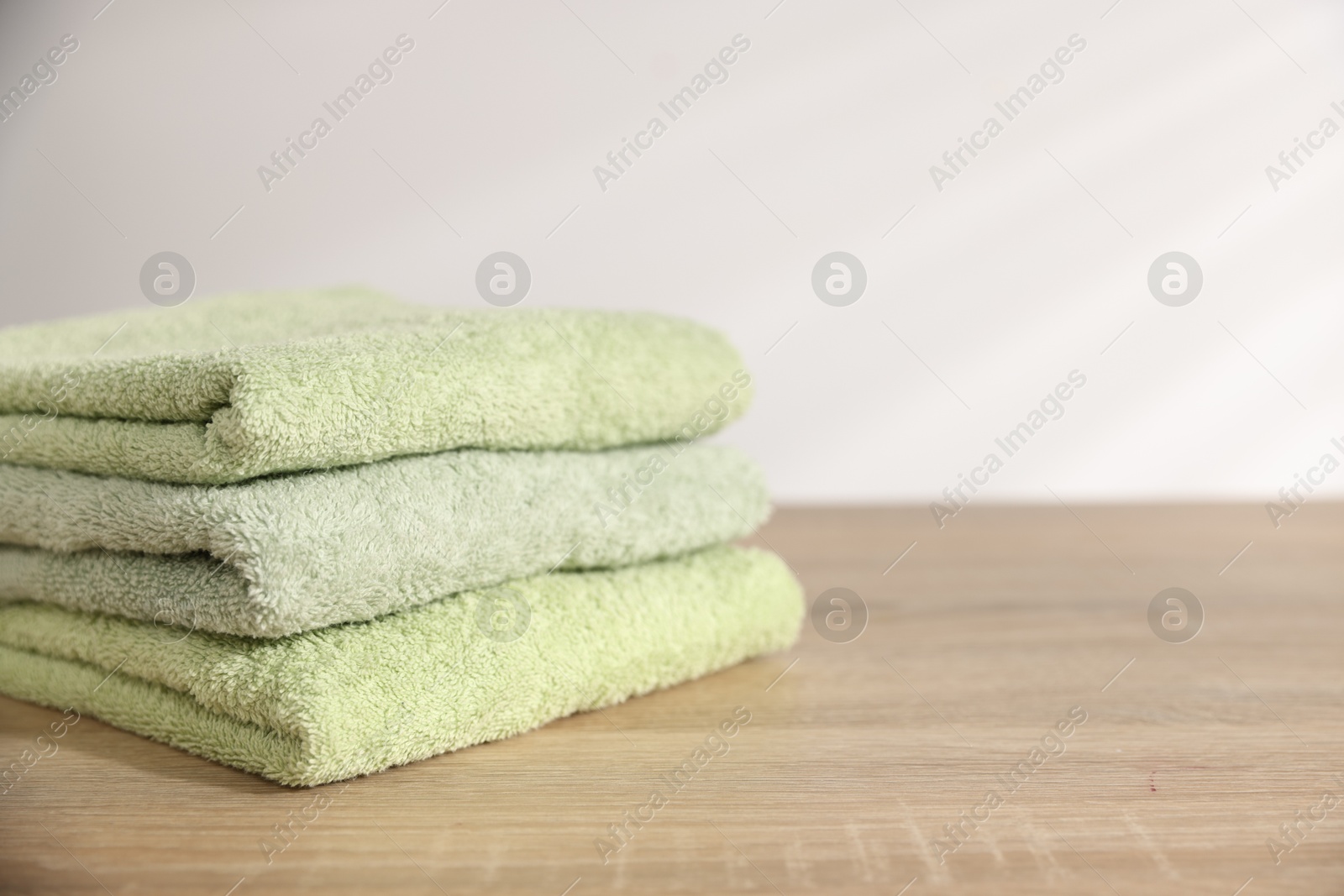 Folded fresh terry towels on wooden table. Space for text Photo of Folded fresh terry towels on wooden table. Space for text