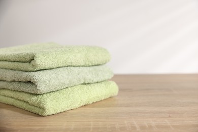 Photo of Folded fresh terry towels on wooden table. Space for text