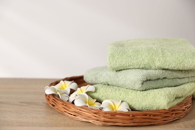 Photo of Fresh terry towels and plumeria flowers on wooden table. Space for text