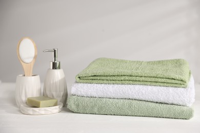 Photo of Fresh terry towels and cosmetic products on white wooden table