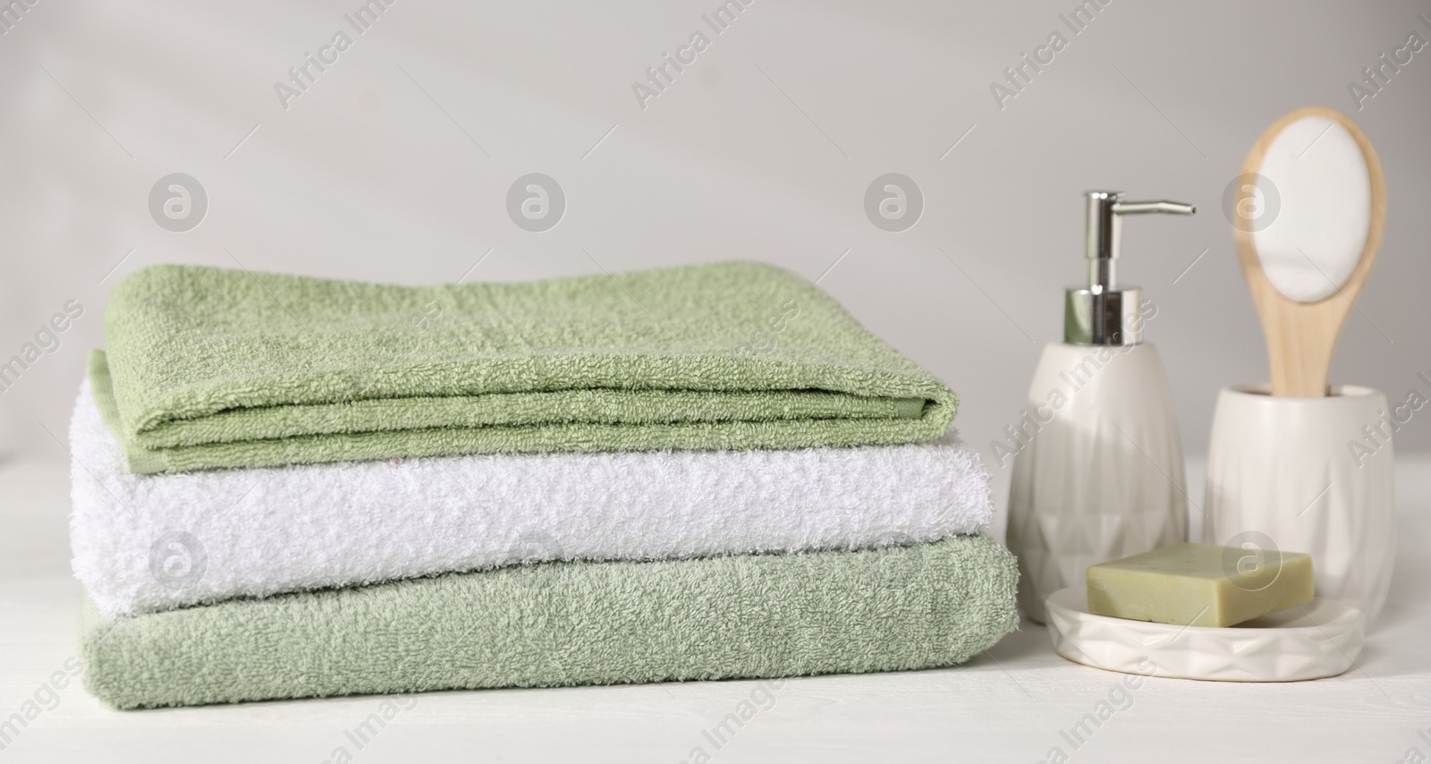 Fresh terry towels and cosmetic products on white wooden table Photo of Fresh terry towels and cosmetic products on white wooden table