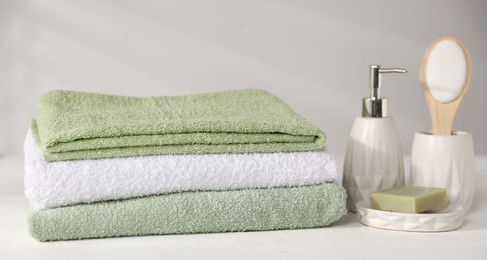 Photo of Fresh terry towels and cosmetic products on white wooden table