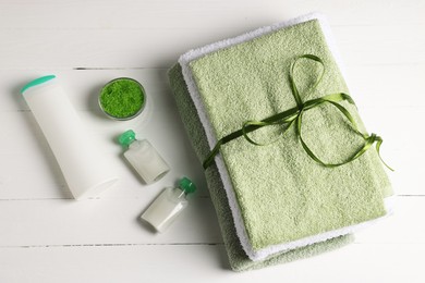 Photo of Fresh terry towels and cosmetic products on white wooden table, flat lay