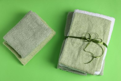 Photo of Fresh terry towels on green background, flat lay