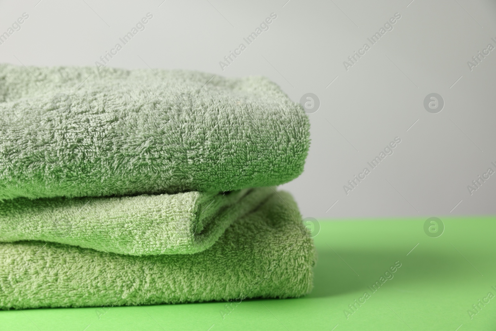 Fresh terry towels on green table, closeup Photo of Fresh terry towels on green table, closeup