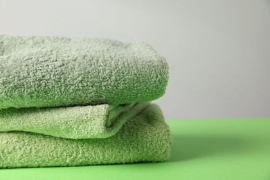 Photo of Fresh terry towels on green table, closeup
