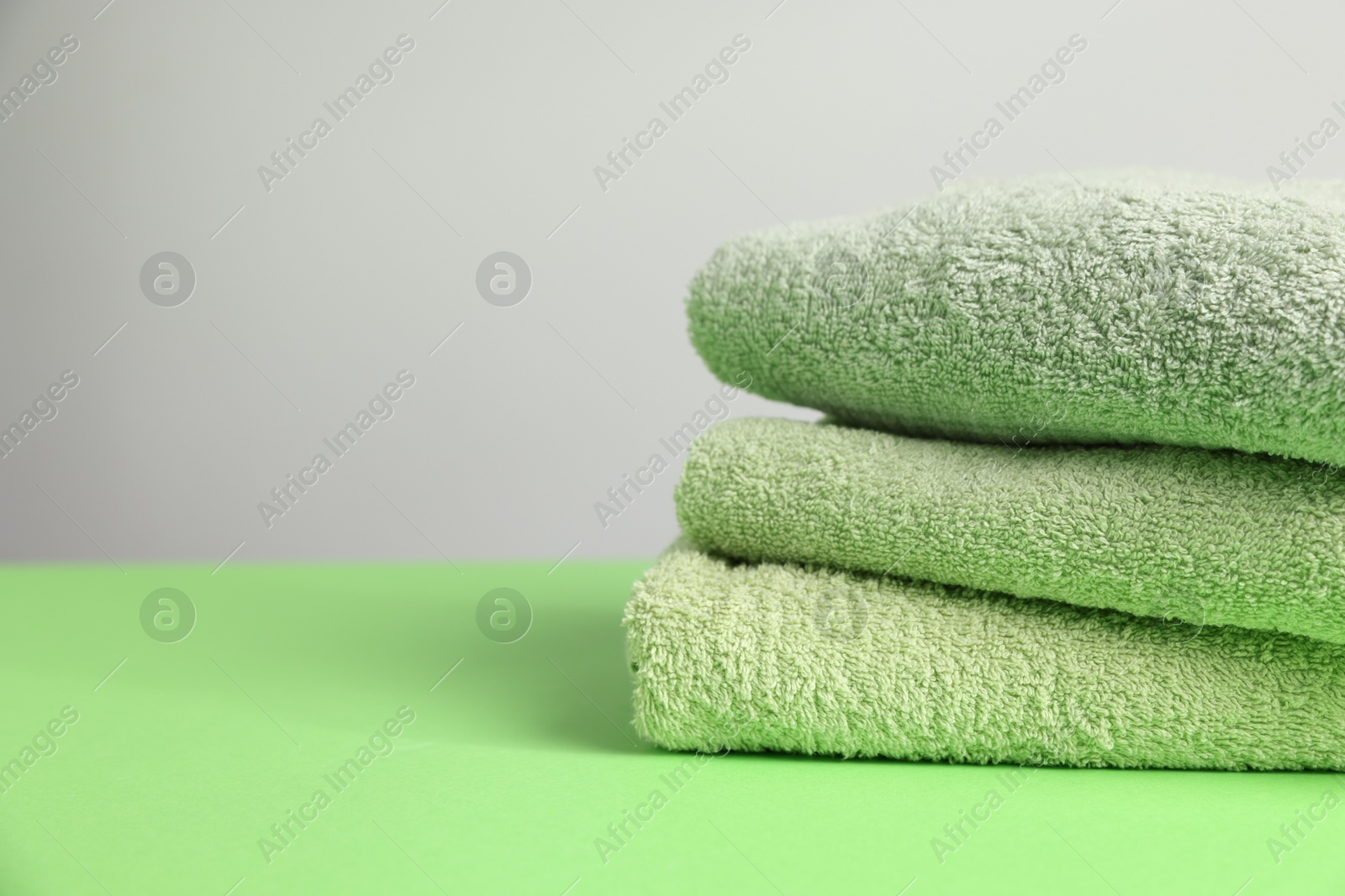 Fresh terry towels on green table, closeup. Space for text Photo of Fresh terry towels on green table, closeup. Space for text