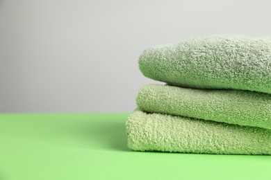 Photo of Fresh terry towels on green table, closeup. Space for text