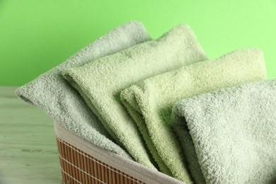 Photo of Fresh terry towels in basket on white table, closeup