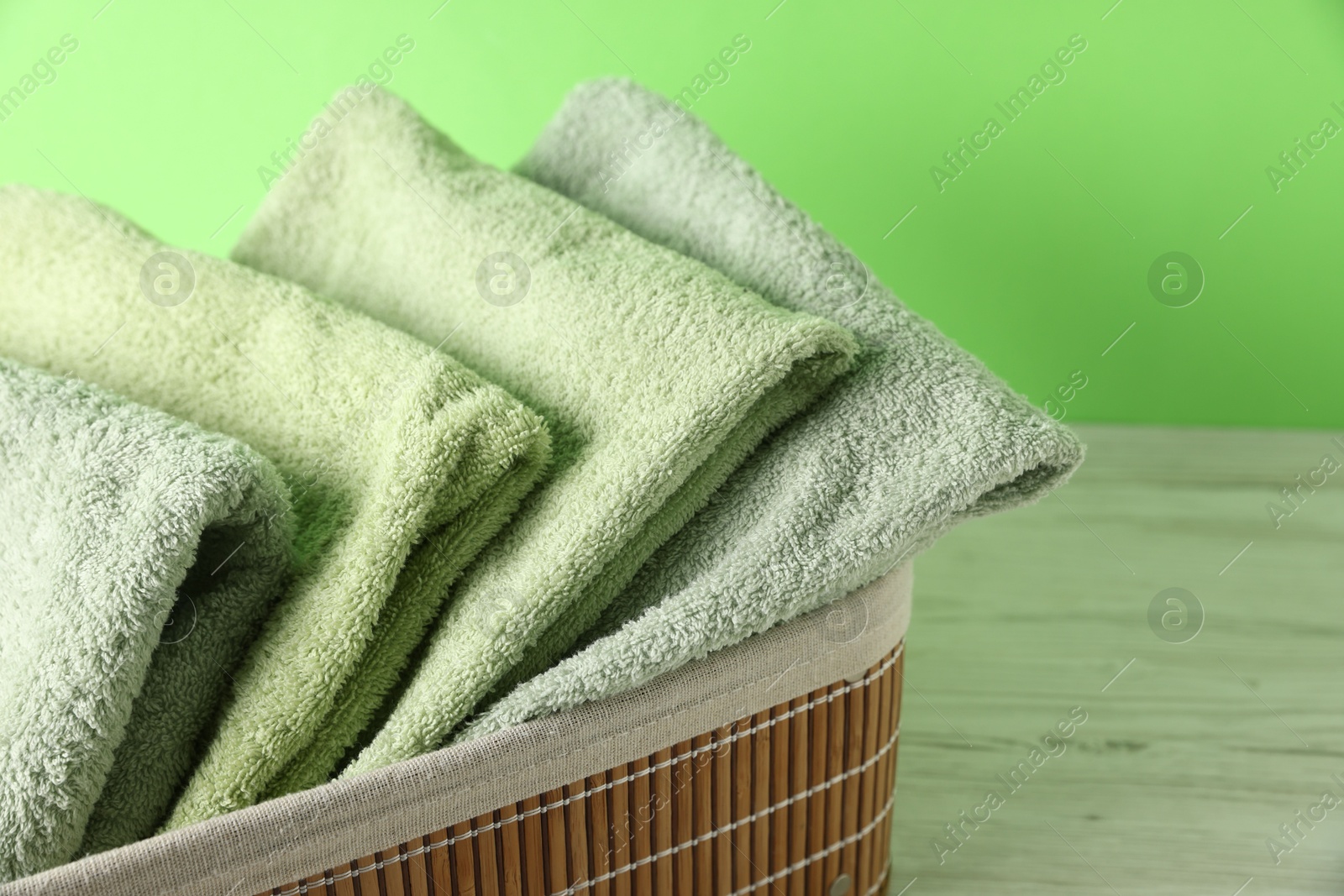 Photo of Fresh terry towels in basket on white table, closeup