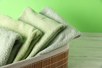 Photo of Fresh terry towels in basket on white table, closeup