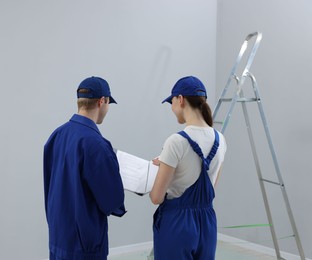 Photo of Workers looking at design project in room, back view