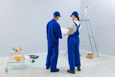 Photo of Workers looking at design project in room, back view