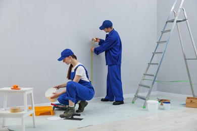 Photo of Workers with different equipment doing renovation in room