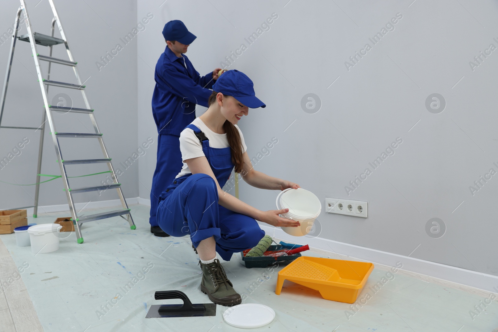 Workers with different equipment doing renovation in room. Space for text Photo of Workers with different equipment doing renovation in room. Space for text