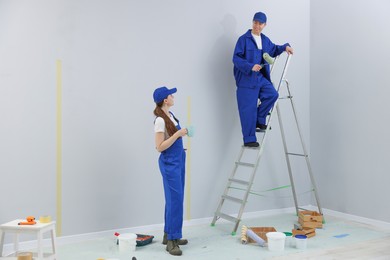 Photo of Woman with coffee and man on ladder renovating room