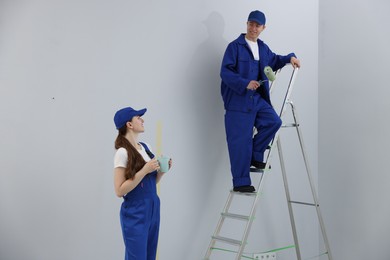 Photo of Woman with coffee and man on ladder renovating room