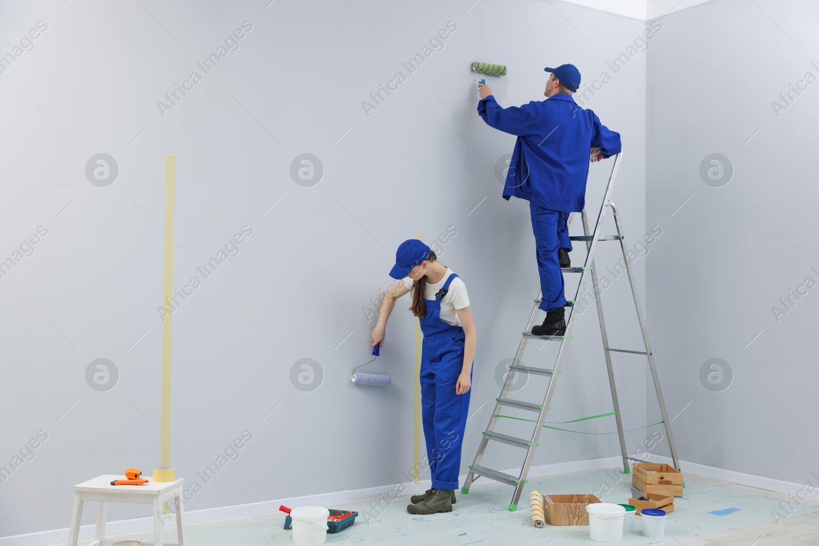 Workers painting wall with rollers in room Photo of Workers painting wall with rollers in room