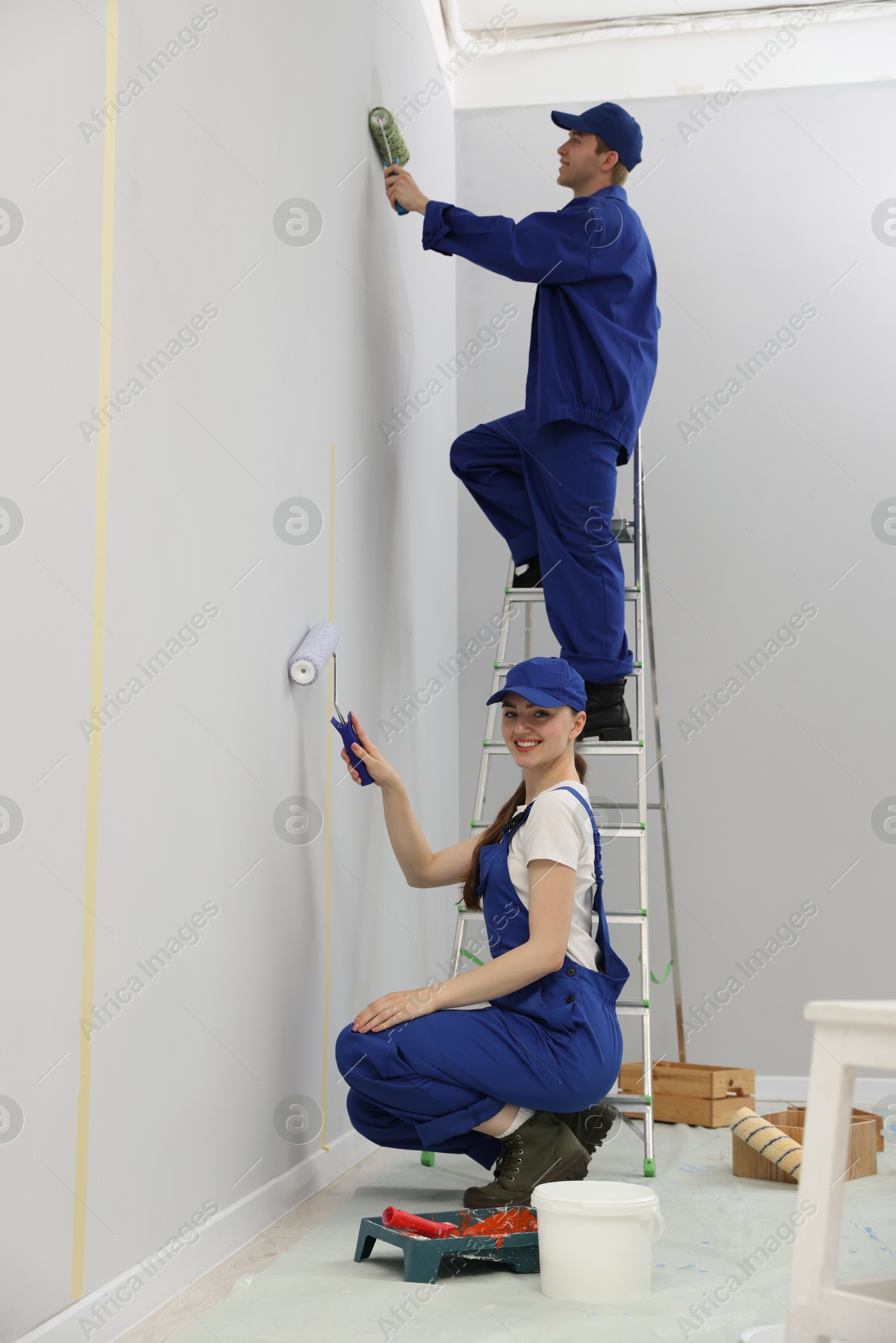 Photo of Workers painting wall with rollers in room