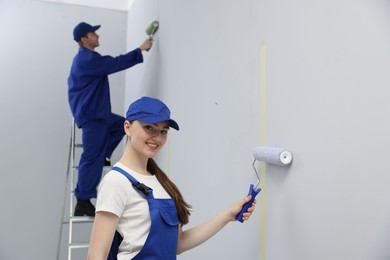 Photo of Workers painting wall with rollers in room