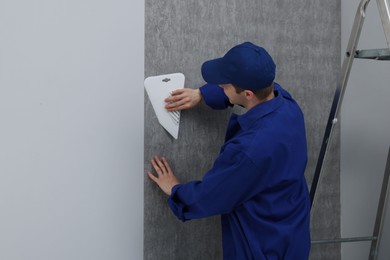 Photo of Worker smoothing wallpaper with tool in room