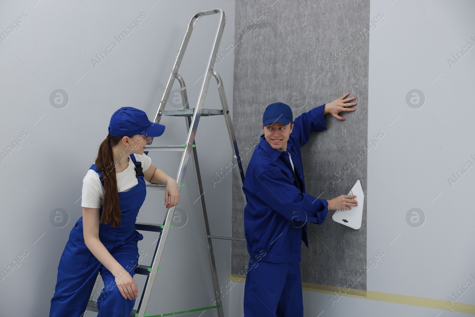 Worker smoothing wallpaper with tool in room Photo of Worker smoothing wallpaper with tool in room