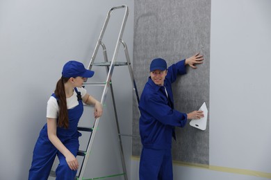 Photo of Worker smoothing wallpaper with tool in room
