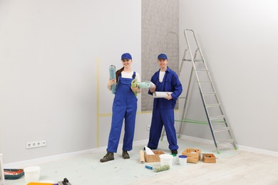 Photo of Workers with rolls of wallpapers in room