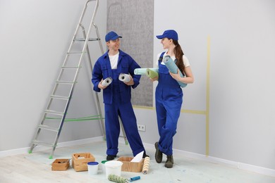 Photo of Workers with rolls of wallpapers in room