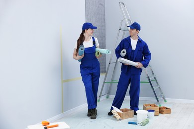 Photo of Workers with rolls of wallpapers in room