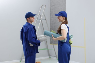 Photo of Workers with rolls of wallpapers in room