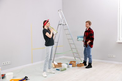 Photo of Couple with rolls of wallpapers in room