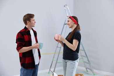 Photo of Couple with cups of coffee having break during renovation in room
