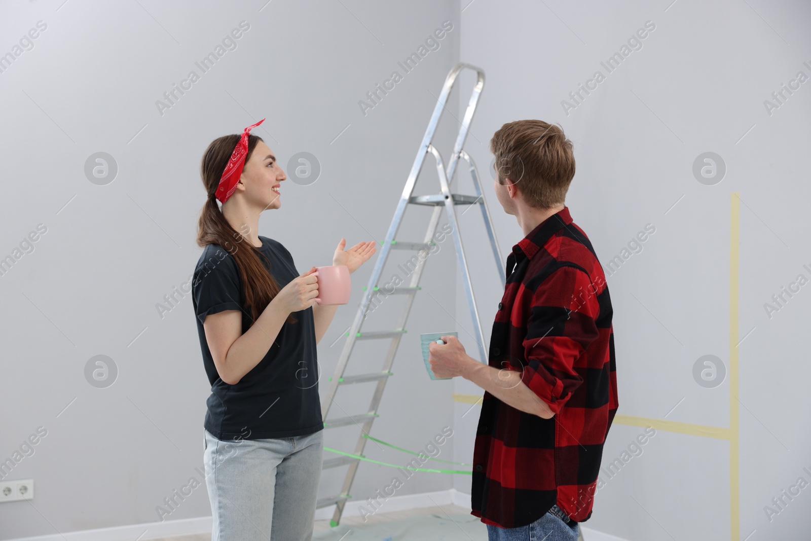 Couple with cups of coffee having break during renovation in room Photo of Couple with cups of coffee having break during renovation in room